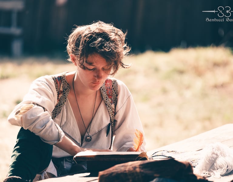 Plan d'une personne en tenue médiévale écrivant dans un livre avec une plume