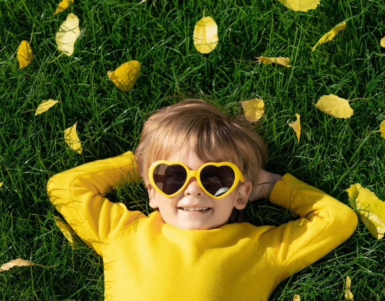 Lachendes Kind mit Sonnenbrille auf Wiese – Selbstvertrauen & Leichtigkeit durch Hypnose für Kinder