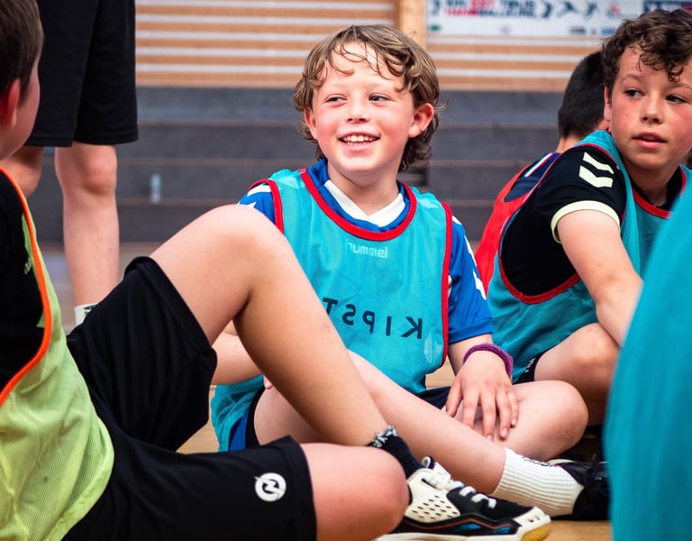 a group of young boys sitting on a basketball court