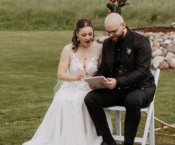 das Hochzeitspaar wird mit einem Video ihrer Lieblingsband überrascht. die beiden blicken erstaunt auf das iPad