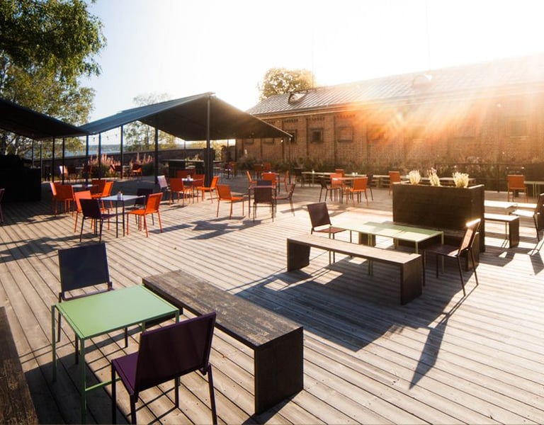 a wooden deck with chairs and tables in the sun