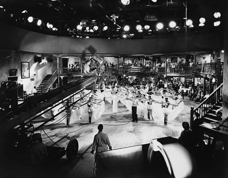 Berkeley on a crane with camera crew, filming white‑skirted dancers in geometric layout.