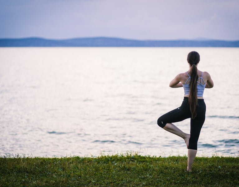 woman doing a yoga pose by the water