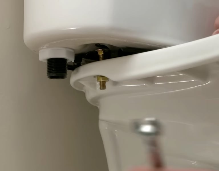 A close-up of a person installing a toilet tank to the bowl with brass bolts for repair.