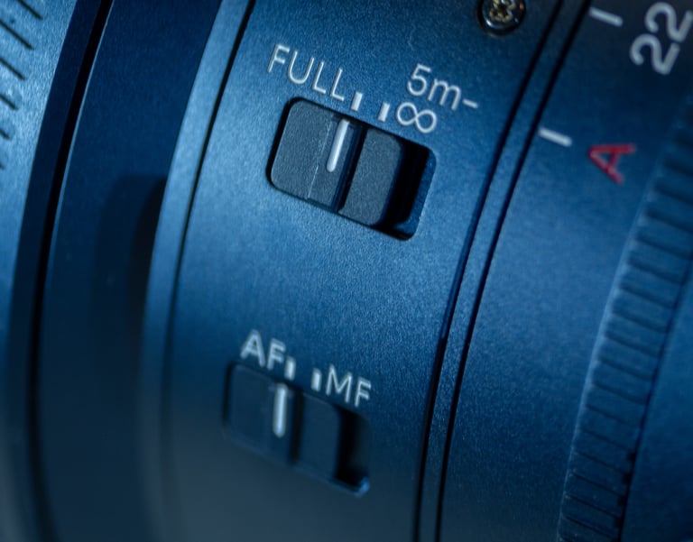 Close-up of a blue DSLR camera lens showing autofocus and manual focus toggle switches.