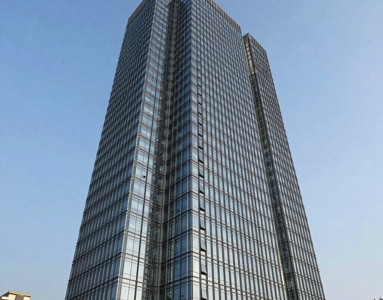 A wide-angle professional photograph of a modern glass skyscraper in a South Asian business district, reflecting a clear blue sky, representing corporate strength and reliability.