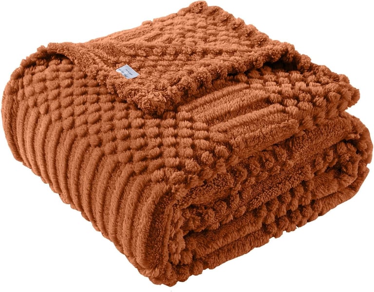 Folded burnt orange textured popcorn throw blanket with soft plush fabric for cozy home decor.