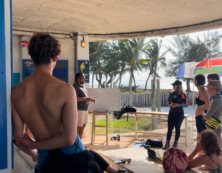 Scuba diving instructor giving a safety briefing to students on a tropical beach.