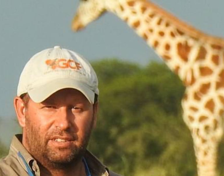 Dr Julian Fennessy in the bush with giraffe in background