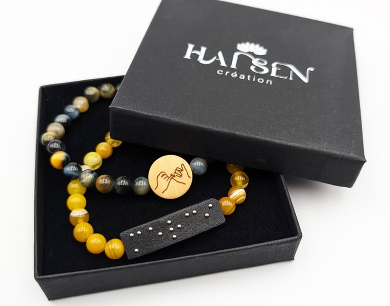 2 Bracelets un avec plaque braille Merci et un avec un cabochon avec le symbole amitié.