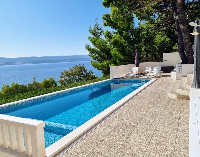The photo shows a pool with a view of the western sun terrace and the sea.