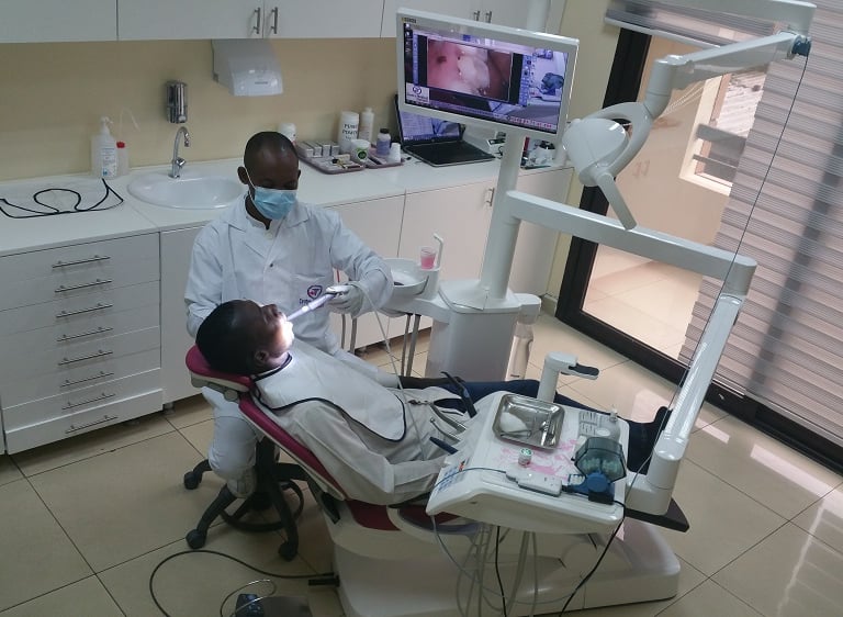 Un dentiste effectuant un examen dentaire sur un patient à l’aide d’une caméra intra-orale à Yaoundé