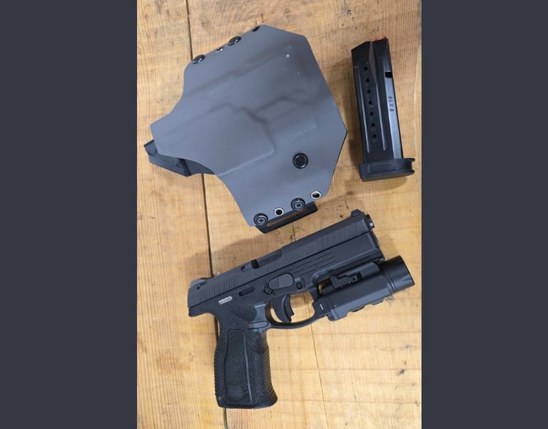 Steyr A2 MF handgun with tactical light, gray Kydex holster, and 9x19 magazine on a wood surface.