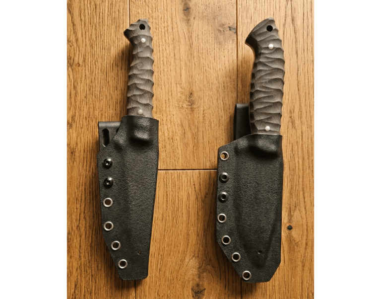 Two custom fixed blade knives with textured G10 handles in black Kydex sheaths on a wooden surface.