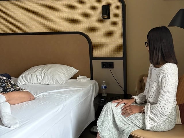 Encadrante assise à côté d'une participante allongée sur un lit lors d'une session privée
