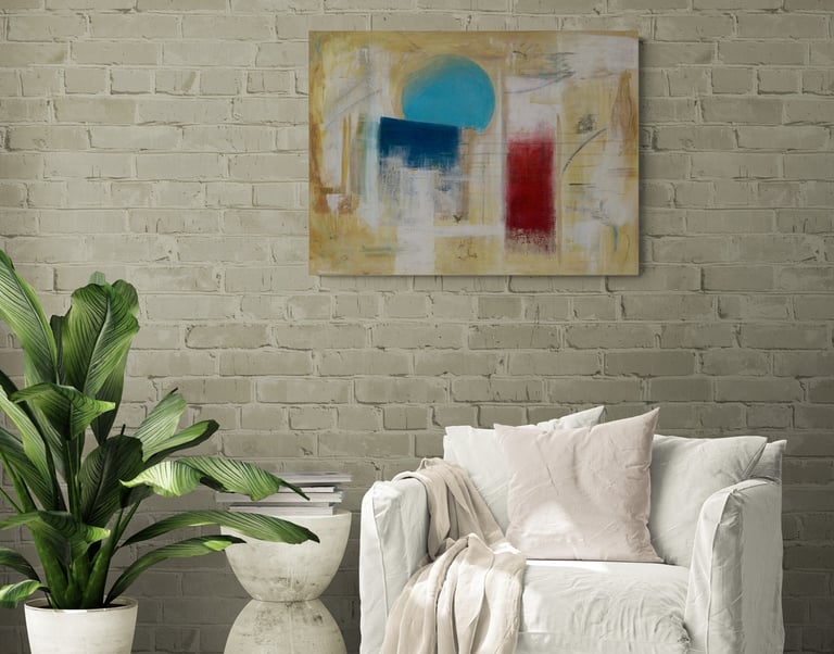 Tan painting with a cerulean sphere on brick wall above white lounge chair.