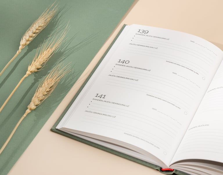 Atverstas dėkingumo žurnalas kasdieniams įrašams, šalia padėtų kviečių varpų.