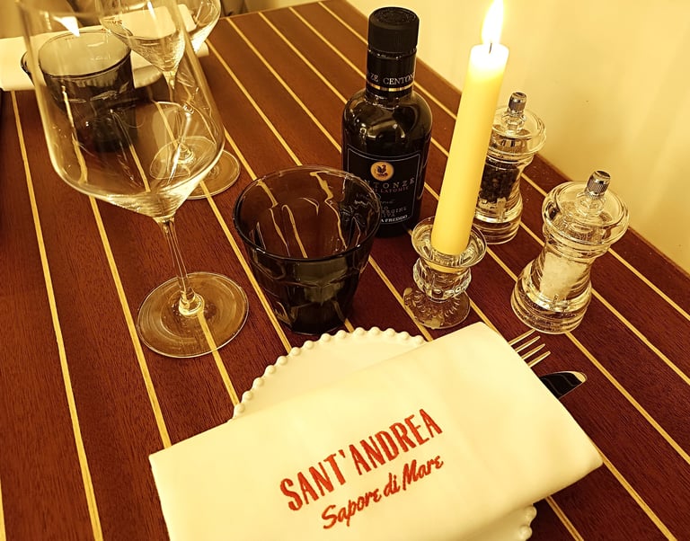 Tavolo apparecchiato al ristorante Sant’Andrea con tovagliolo ricamato e bottiglia di olio Centonze