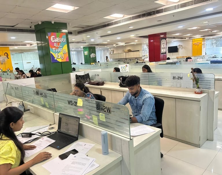 Diverse employees working at desks in a modern open-plan office workspace with laptop computers 