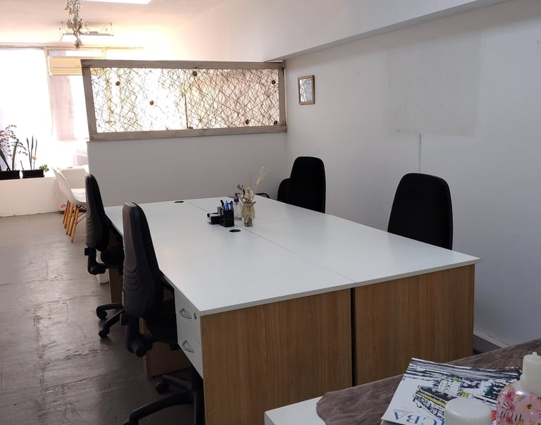 Espacio de trabajo en Red de Llaves con escritorios individuales, silla blanca y luz natural tenue.