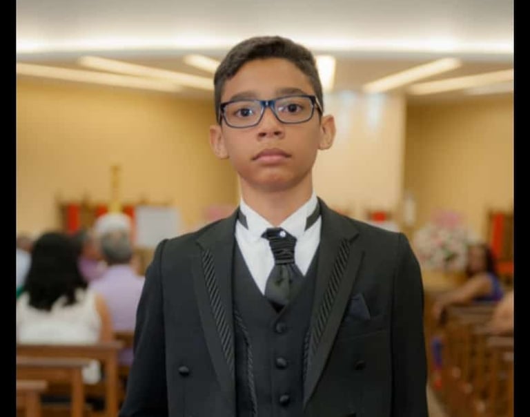 Foto de um garoto vestido com um terninho fino, de otima qualidade.