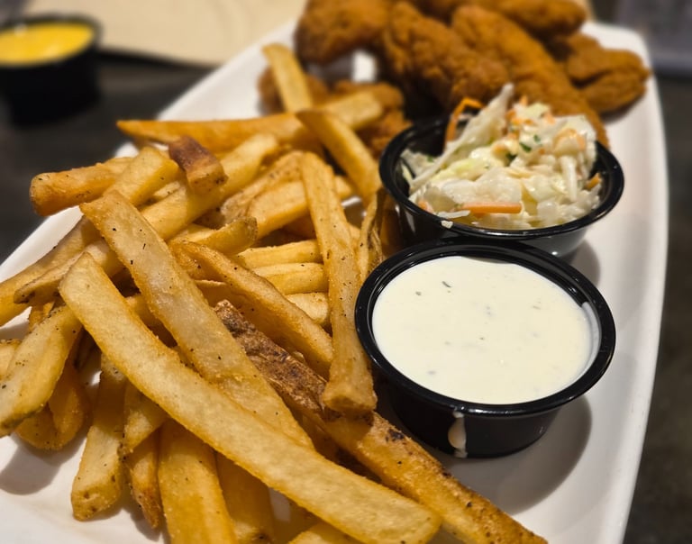 french fries, ramekin of ranch, coleslaw, and chicken fingers 