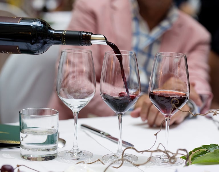 Der Kellner schenkt Rotwein in ein Glas ein.
