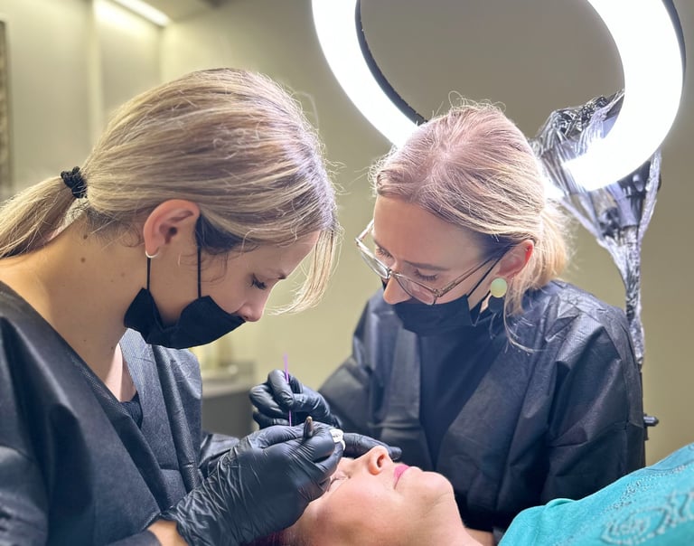 Darina y su estudiante haciendo cejas para una clienta