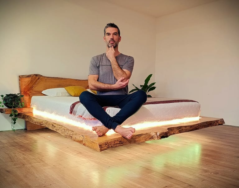 The founder of Axel Atelier sitting on a bespoke live edge floating bed, showcasing structural integ