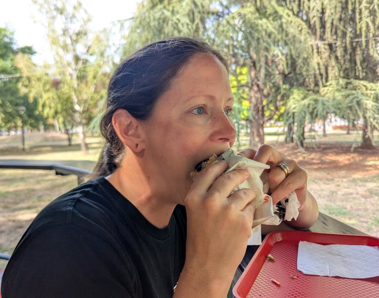 Bugs eating a burger on an outdoor patio with trees in the background.