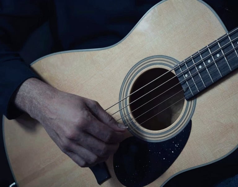 An abstract, artistic photograph capturing the vibration of guitar strings in motion. The lighting is moody and sophisticated, utilizing dark midnight blue tones and a soft off-white glow to highlight the movement.