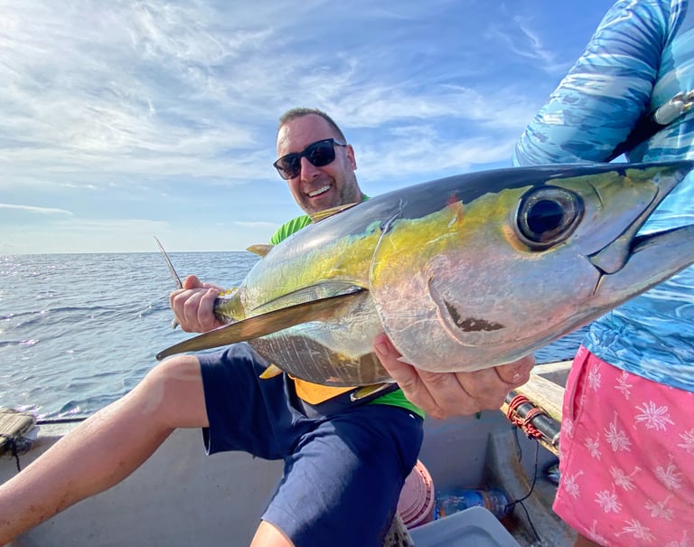 A man holding a fish in his hands during a Zanzibar fishing charter, perfect for Zanzibar fishing