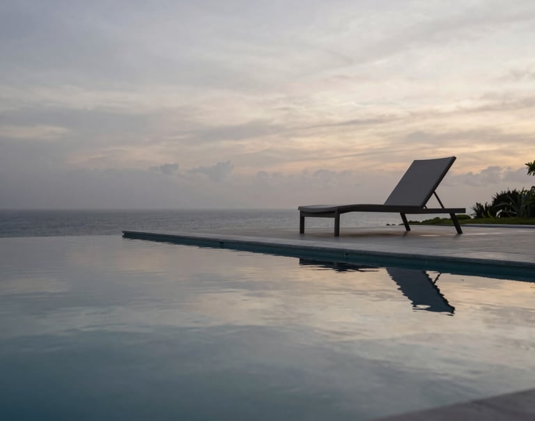 A detail shot of a black infinity pool reflecting the silver grey sky at dawn. A single minimalist lounge chair sits on the edge. The setting is a private estate in a South American / Brazilian coastal region. Sophisticated and exclusive atmosphere.