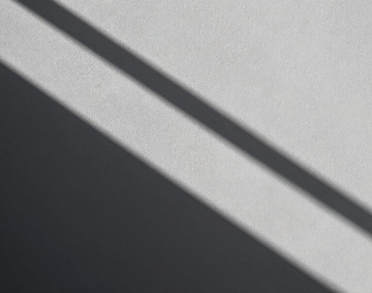 A study of geometric shadows cast across a textured light gray wall, sharp diagonal lines, high contrast monochromatic photography, minimalist and balanced composition, North American / European.