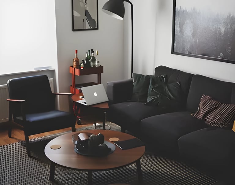 Modern living room with black leather sofa and laptop, illustrating accommodation options forstudent