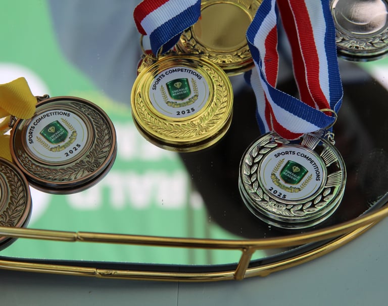 Gold, silver, and bronze sports competition medals with ribbons for the 2025 Emerald Academy awards.