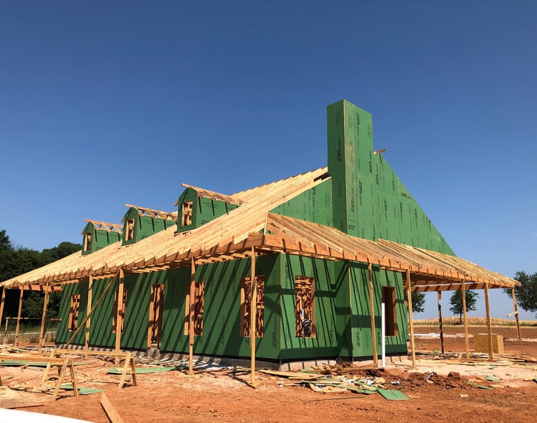 a house being built with green siding and wood framing