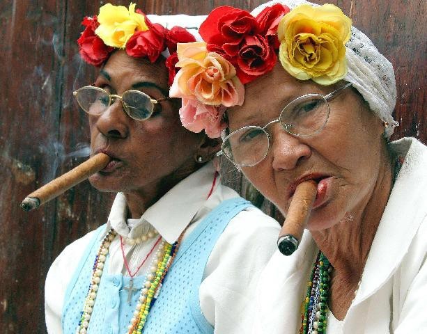two elder Santeria brujas wearing white and smoking cigars