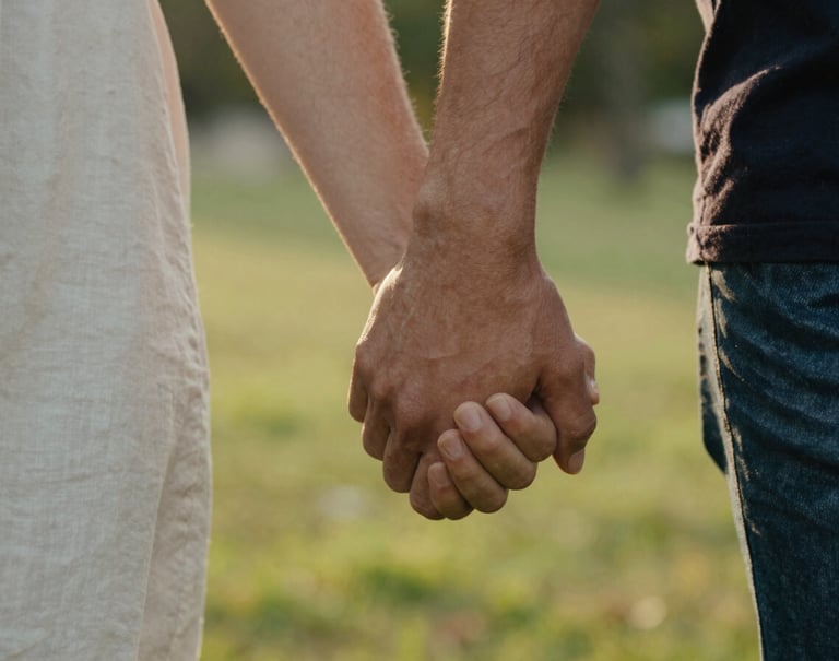 A close-up, shallow depth-of-field photograph of two people holding hands while walking in a North American park. The light is warm late-afternoon golden. Focus on the authentic connection and skin texture.