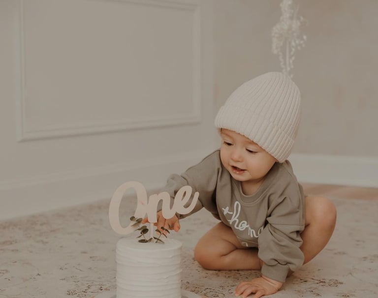 a baby boy is sitting on the floor with a cake