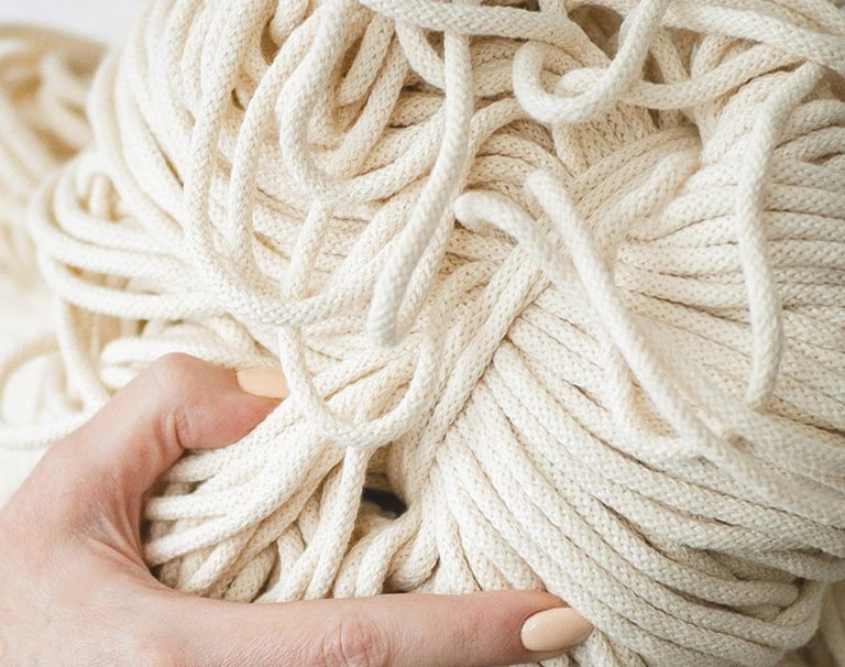 manos sosteniendo una bola de cordón de macramé