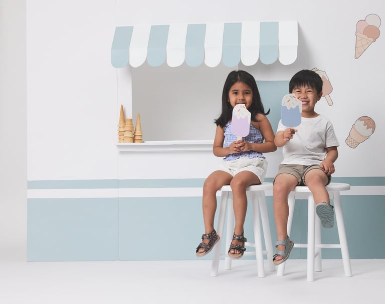 Fashion campaign photography - two children sitting on stools in front of a ice cream shop