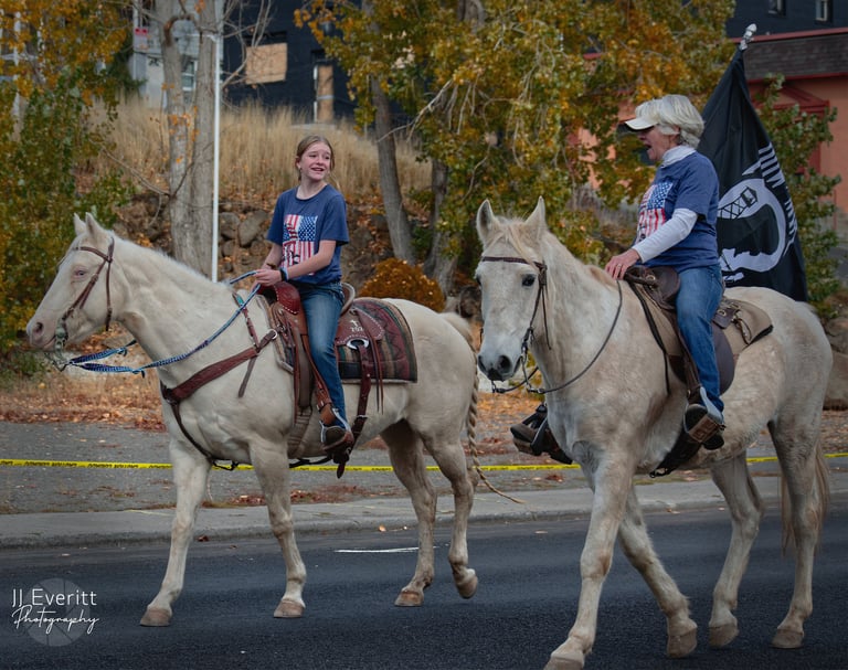 a young woman and older woman riding horses down a street