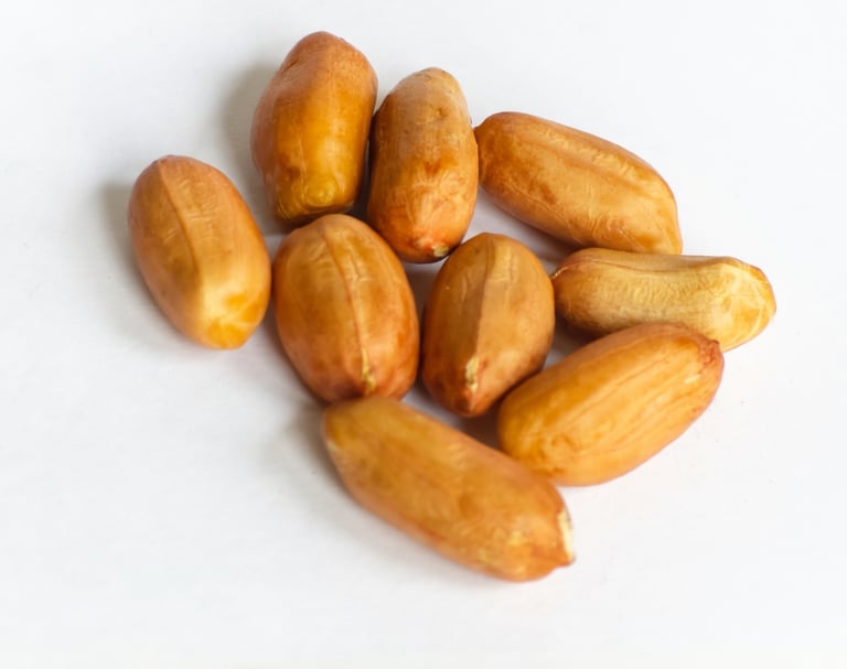 A small pile of shelled raw peanuts with red skins isolated on a white background.