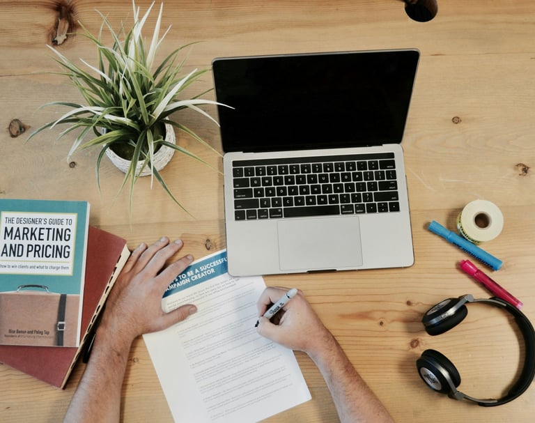 A person working on a paper with a computer and books nearby