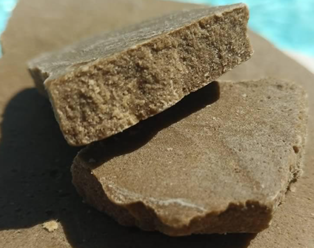 Hachís de CBD natural prensado sobre fondo marrón claro