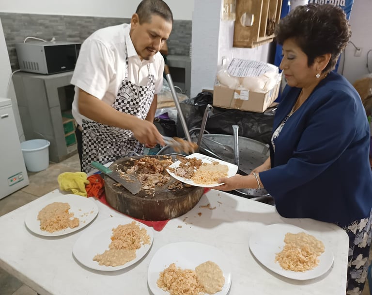Cocinero sirviendo barbacoa en un evento, con platos de arroz y frijoles listos para los invitados.