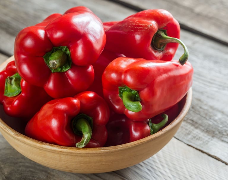 a bowl of red peppers on a wooden table