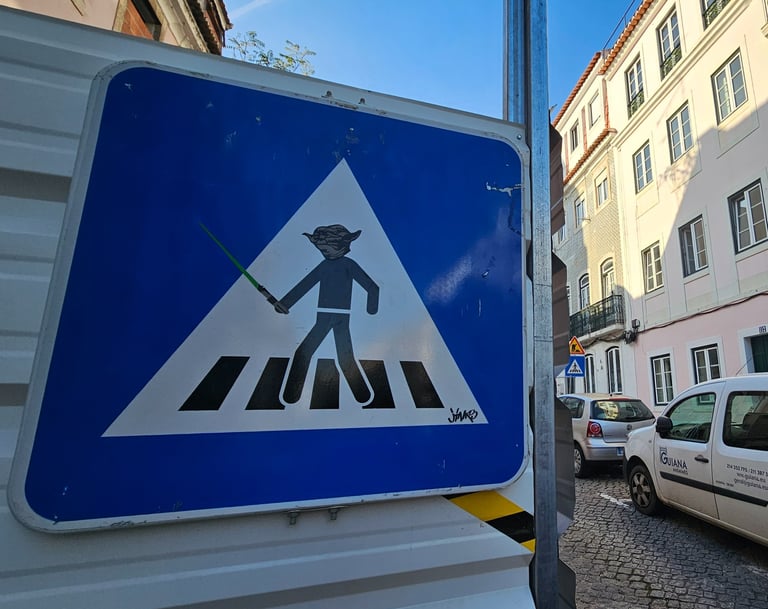 Street art sur panneau de signalisation représentant Yoda sur un panneau piéton à Lisbonne.