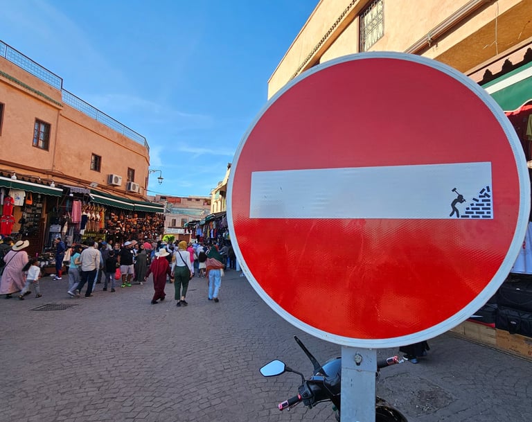 Détournement de panneaux de signalisation représentant un homme détruisant un mur sur sens interdit